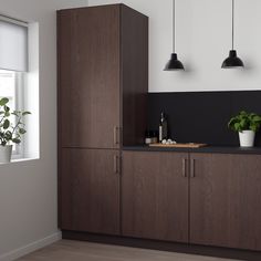 a kitchen with wooden cabinets and black counter tops next to a potted plant on a window sill