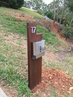 a mailbox on the side of a hill with trees in the background