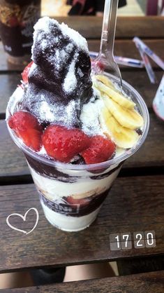 an ice cream sundae with strawberries, bananas and powdered sugar on top