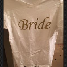 a white t - shirt with the word bride on it hanging from a clothes rack