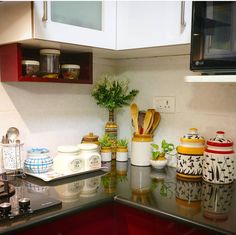 the kitchen counter is covered with pots and pans, including one that has a plant in it