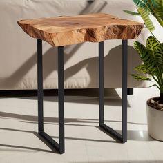 a wooden table sitting on top of a white floor next to a potted plant