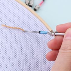 someone is holding a needle and thread in front of a piece of fabric that has been stitched together