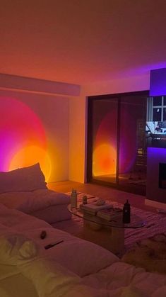 a living room filled with lots of white furniture and colorful lights on the wall behind it