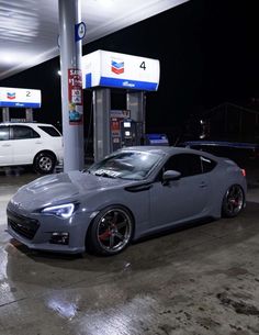 a grey sports car parked at a gas station