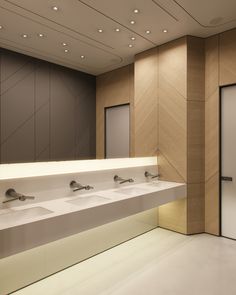 a row of sinks in a bathroom with lights on the ceiling and wall behind them