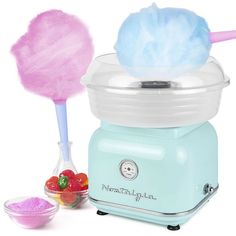 an ice cream maker with two cotton balls in it and a bowl of strawberries next to it