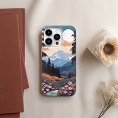 the phone case is designed to look like it has mountains and trees on it, along with flowers