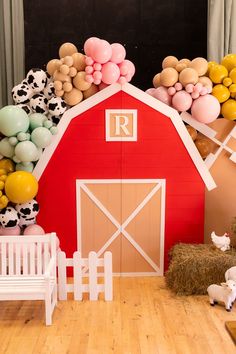 a red barn with balloons and farm animals on the floor next to hay bales