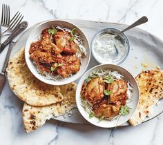 three bowls filled with food on top of a white plate next to pita bread