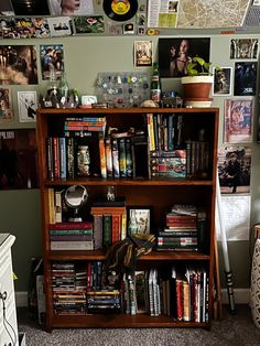 a bookshelf filled with lots of books next to a wall covered in pictures