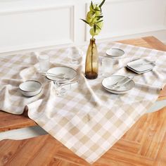 the table is set with white dishes and flowers in a vase on top of it