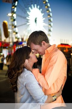 a man and woman standing next to each other in front of a ferris wheel