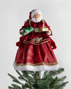 a christmas ornament on top of a tree with a santa clause hat and red dress