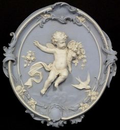 a white and blue plaque with a cherub on it's face, surrounded by birds