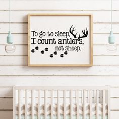 a baby's room with a crib and wall hanging above it that says to go to sleep i count antlers not sheep