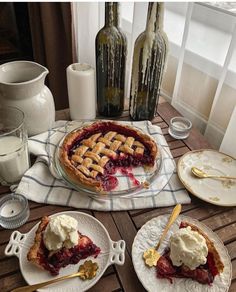 a table topped with plates and desserts next to wine bottles