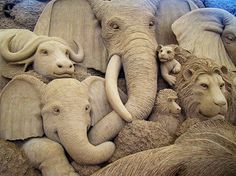 a group of elephants laying next to each other on top of sand sculptures in the shape of animals