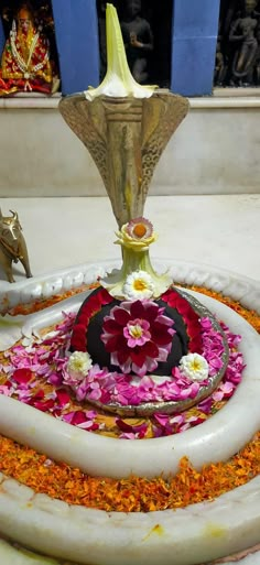 a fountain with flowers on the bottom and water flowing from it's sides, surrounded by other decorations