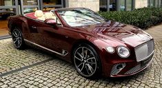 a red convertible car parked in front of a building on a cobblestone street