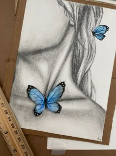 a drawing of a woman's face with two blue butterflies on her chest, next to a ruler