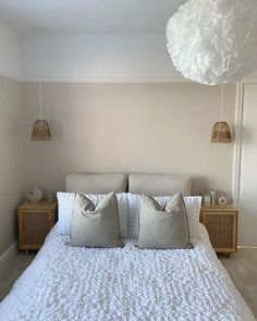 a bed with white linens and pillows in a small room next to a wall