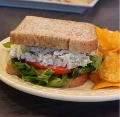 a sandwich with lettuce, tomato and chicken on it next to chips in a bowl