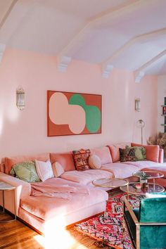 a living room with pink couches and colorful rugs on the wooden flooring