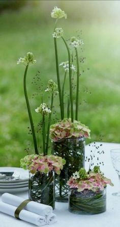 there are three vases with flowers in them on the table