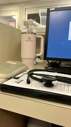 a laptop computer sitting on top of a desk next to a cup and coffee mug