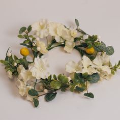 white flowers and green leaves are arranged in a circle