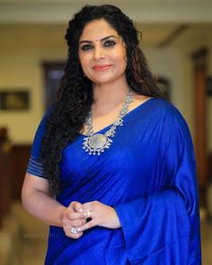 a woman in a blue sari posing for the camera with her hand on her hip