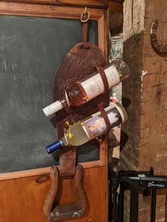 a wine bottle holder made out of an old wooden board with two bottles hanging from it