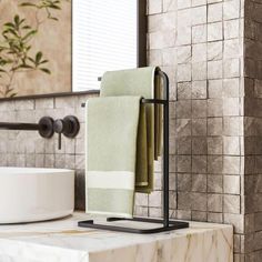 towels are hanging on a towel rack in a bathroom with marble walls and flooring