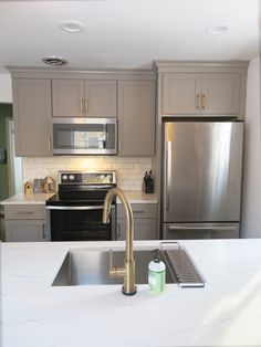 a kitchen with stainless steel appliances and white counter tops, along with a silver refrigerator freezer