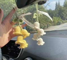 someone is holding their hand on the steering wheel of a car with crocheted decorations hanging from it