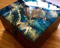 a wooden box sitting on top of a hard wood floor covered in blue and white paint