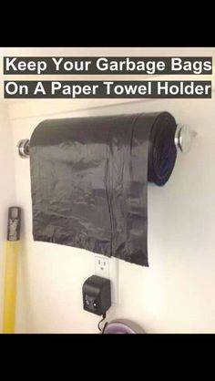 a black towel holder hanging from the side of a wall next to a roll of toilet paper