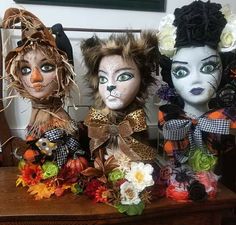 three stuffed animals sitting on top of a wooden table covered in leaves and flowers next to each other