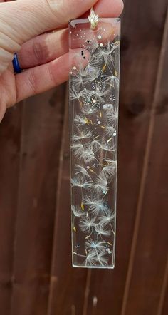 a hand holding a clear tube filled with dandelions and other small things in it