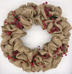 a burlap wreath with red berries and green leaves