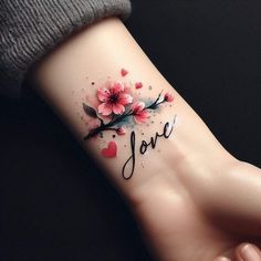 a woman's wrist tattoo with flowers and the word love written in cursive writing