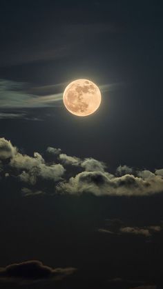 the full moon is shining brightly in the dark night sky with fluffy clouds around it