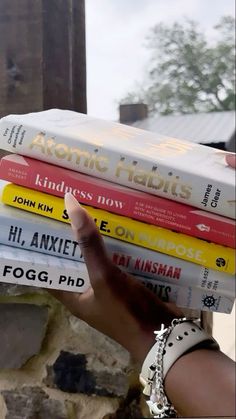 a stack of books sitting on top of each other in front of a brick wall