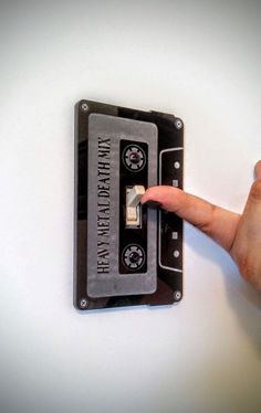 a hand is pressing the button on an old fashioned cassette