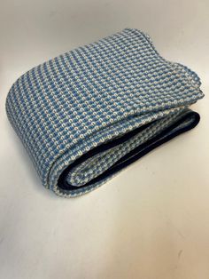 a blue and white checkered blanket folded on top of a table next to a pair of scissors