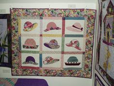 a quilted wall hanging with hats on it