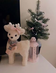 a white stuffed animal standing next to a small christmas tree