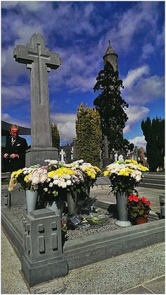 a man standing in front of a grave with flowers on it