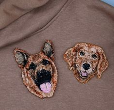 two dogs embroidered on the back of a brown shirt with their tongue out and one has its mouth open